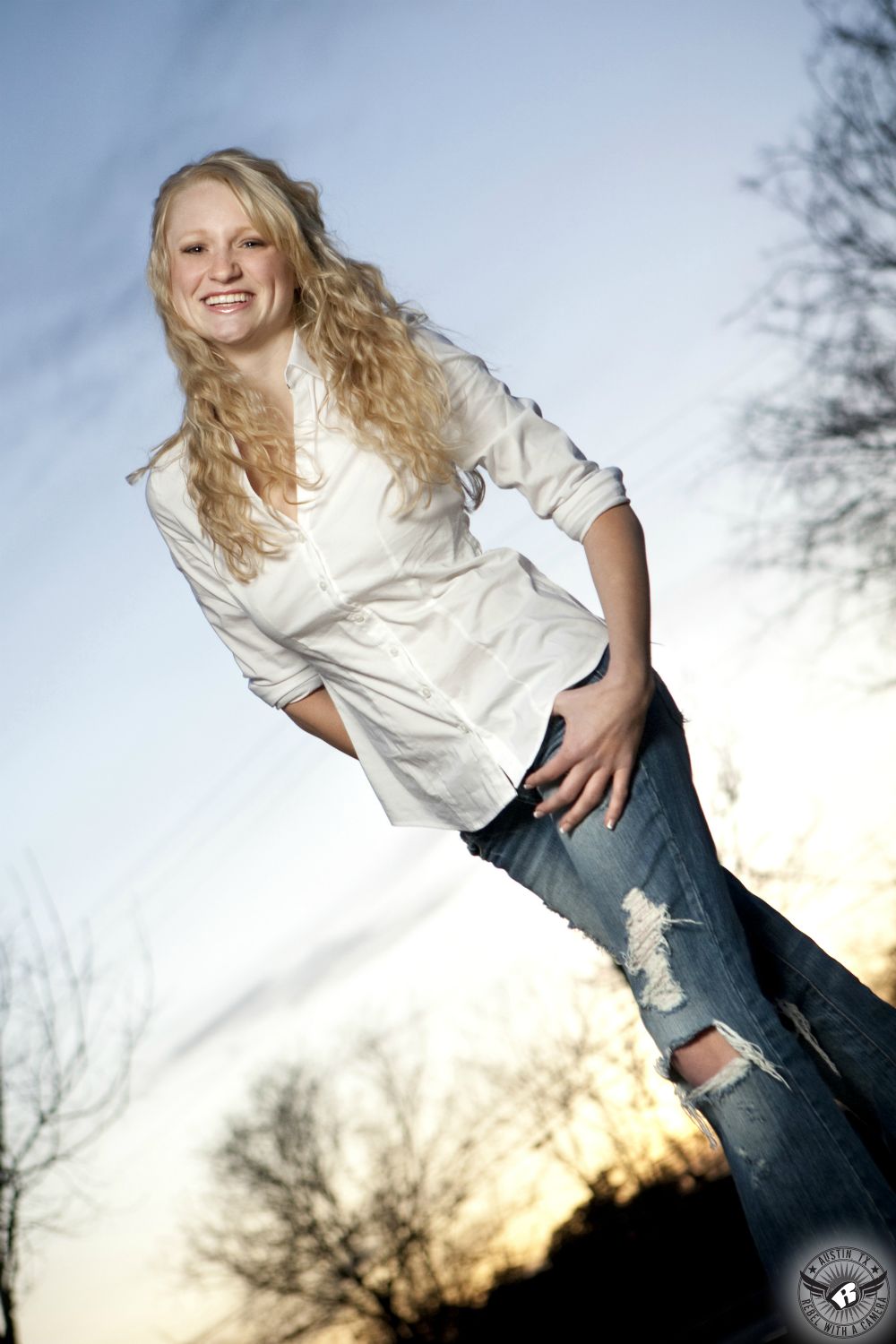 Outdoor senior portrait photography in Austin of blonde girl with sunset behind.